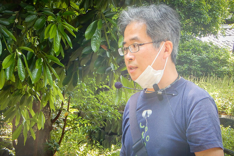 マイクを使って説明する本田創さん。屋外なので、周囲と十分な距離を取れる場所ではときどきマスクを外し、熱中症を予防