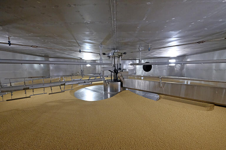 麹菌を加えた大麦は麹室（こうじむろ）に送られる。麹室は巨大な回転式のもので、高さが均等になるように調整していく。あとは麹菌の力で「大麦麹」が作られていく