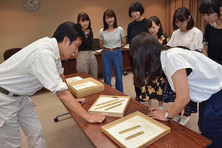奈良文化財研究所（奈良市）で、食材の名前が記載された木簡を見学するゼミ生（写真提供：三舟隆之）