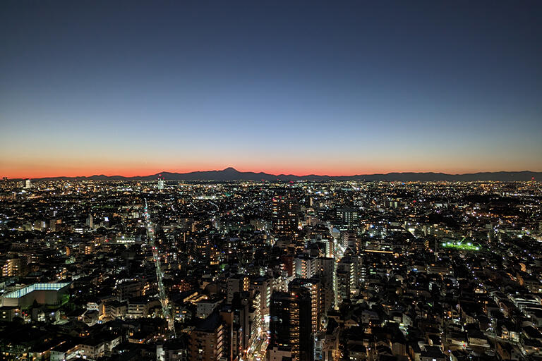 高層ビルからの日没直後のカットです。空を美しく表現するにはマジックアワーと呼ばれる日没前後がチャンスです。ブルーの色が空に残っている時間がいいですよ。丹沢を従えた富士山のシルエットと稜線の形、街中の灯りをいい感じに撮影できました