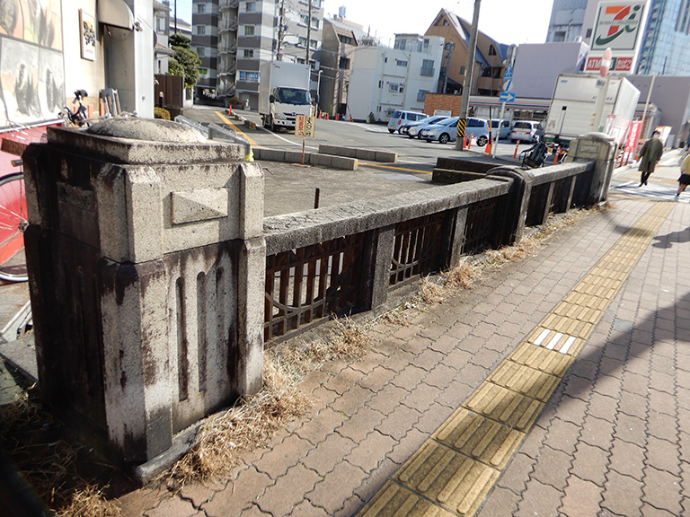 残された立派な親柱と欄干。橋名板は見当たらなかった。奥のコンクリートの部分は蓋をされた暗渠に見える。手前の金華通りと斜めに交差していた